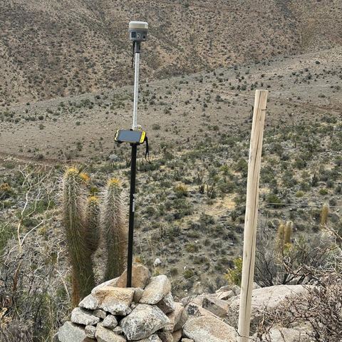 Receptor GNSS sobre un mojón de deslinde en terreno árido.